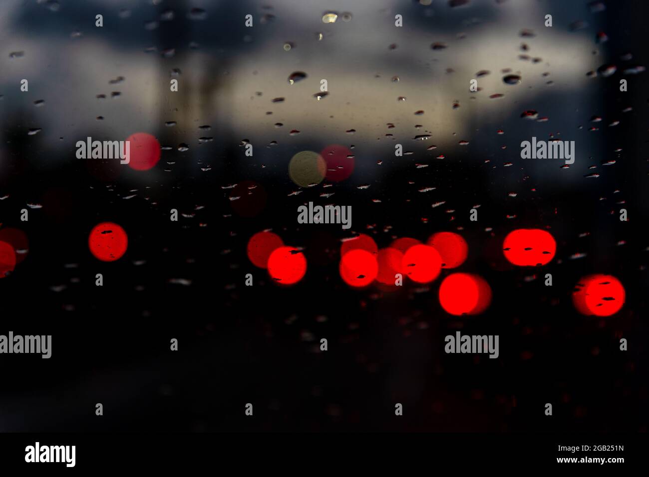 Colored lights blur through the car window, wet with raindrops. Heavy