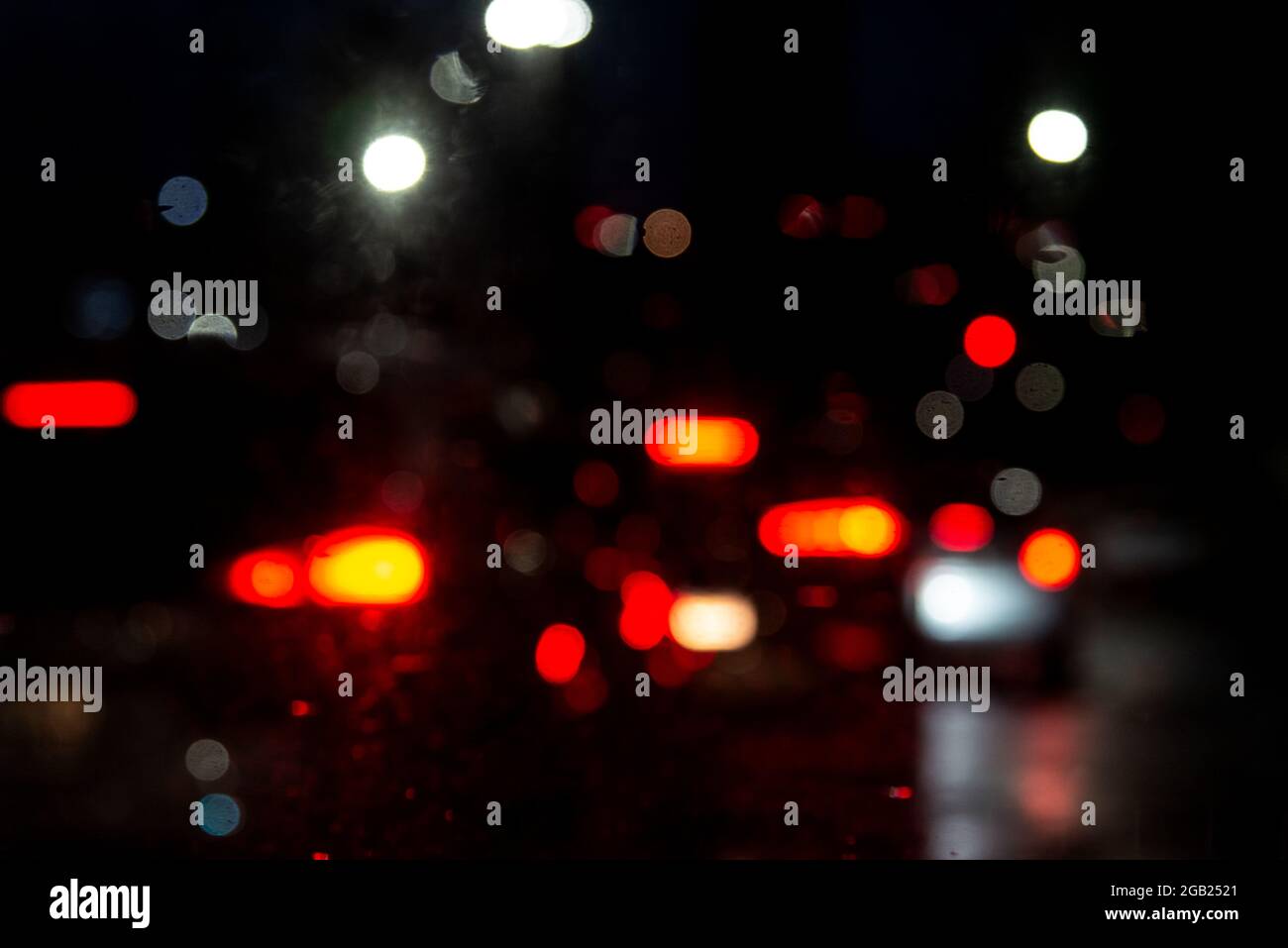 Colored lights blur through the car window, wet with raindrops. Heavy