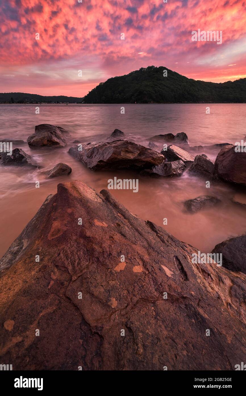 stunning bright pink sunrise at the beach from the rocks Stock Photo
