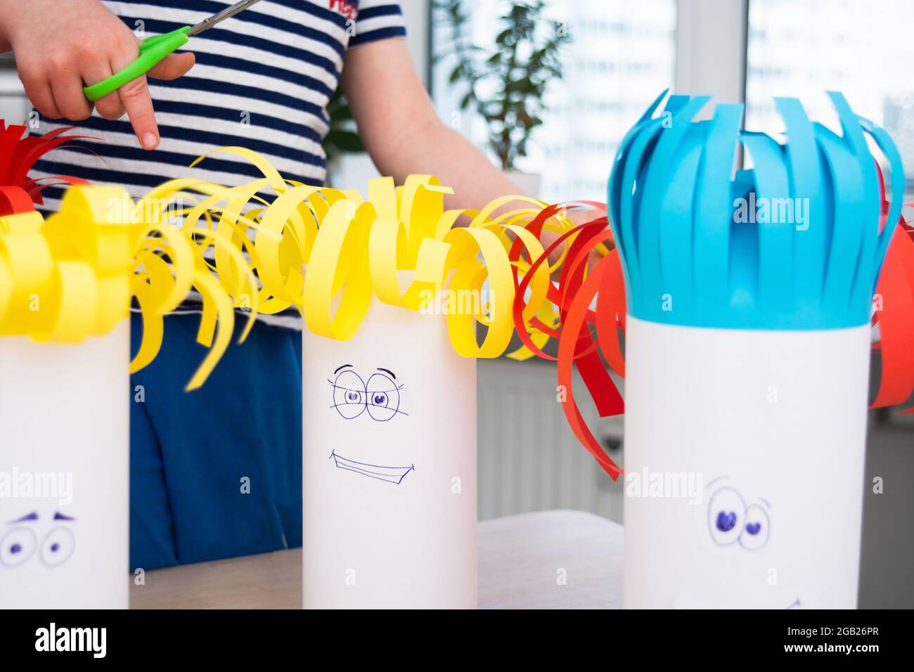 Preschool boy cutting paper hair with scissors on handmade funny heads ...