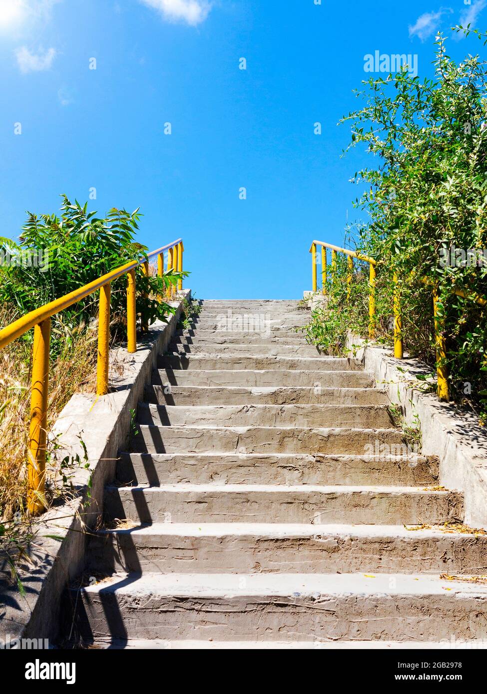 Architectural elements of the old concrete stairs with yellow railing up, backlit Stock Photo