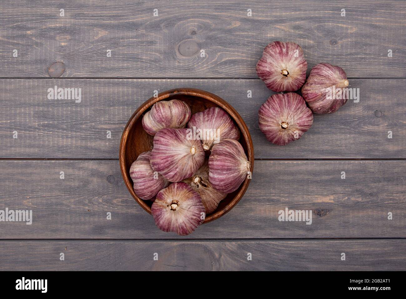 Garlic bulbs in a wooden plate on a wooden table. Rustic style Stock ...