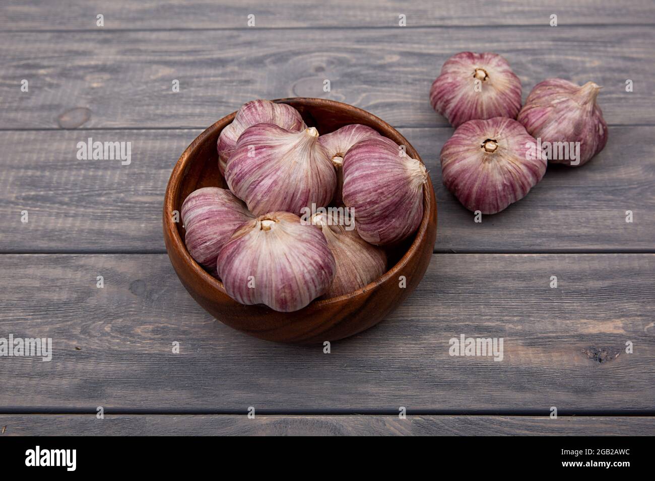 Garlic bulbs in a wooden plate on a wooden table. Rustic style Stock ...