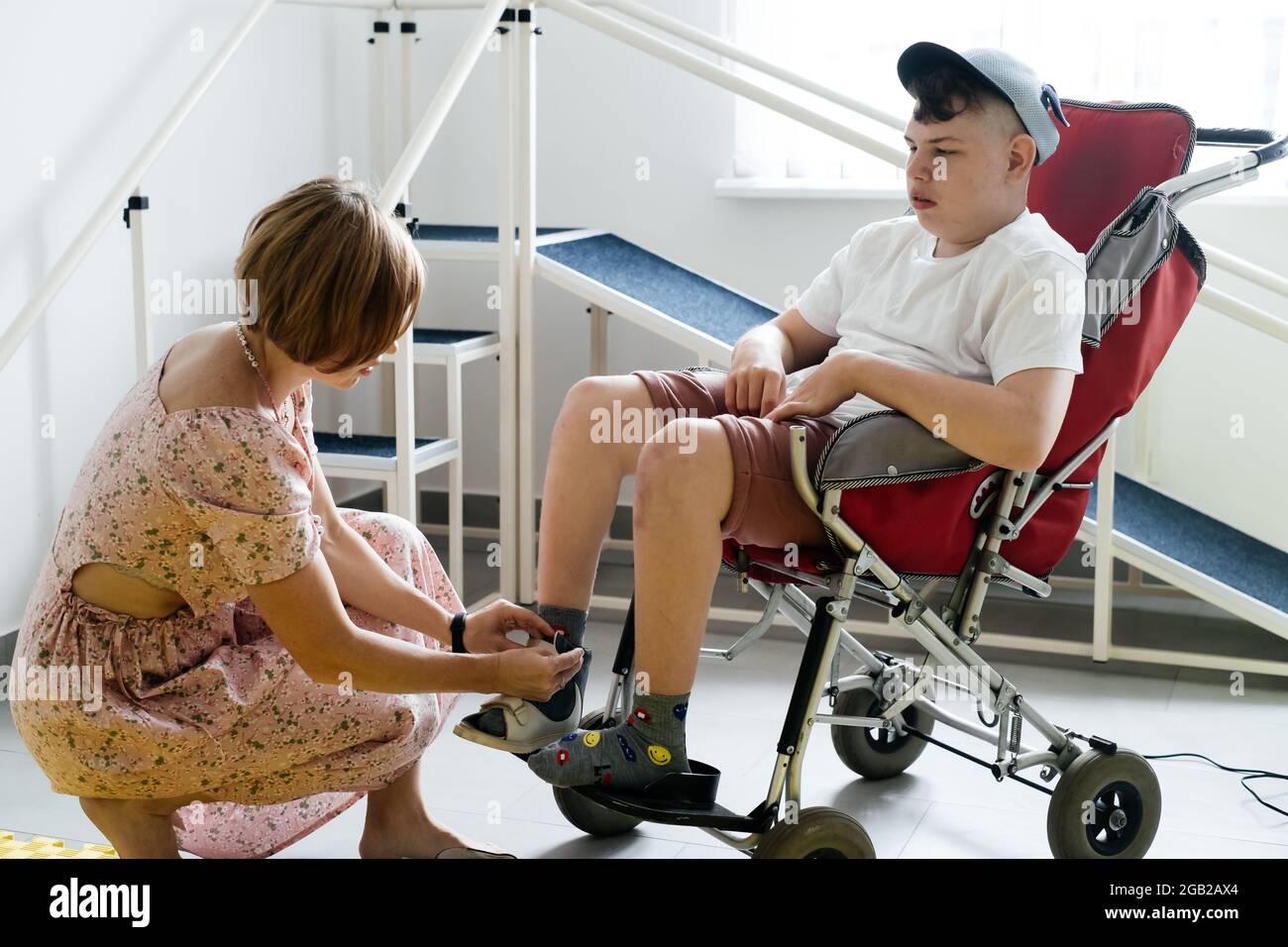 Mother helping disabled boy 17 years old in wheelchair with cerebral