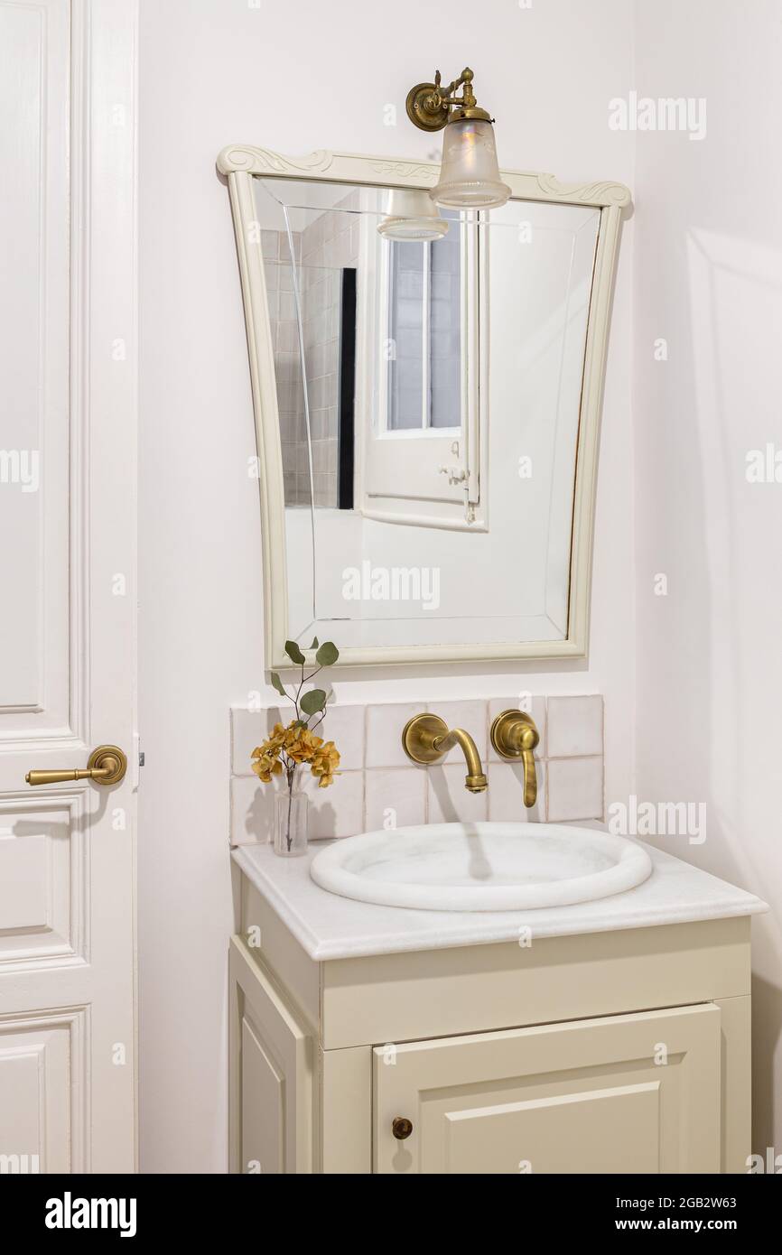 Bathroom decorated in beige color with small sink, bronze faucet and  vintage mirror. Interior of retro or classic style Stock Photo - Alamy