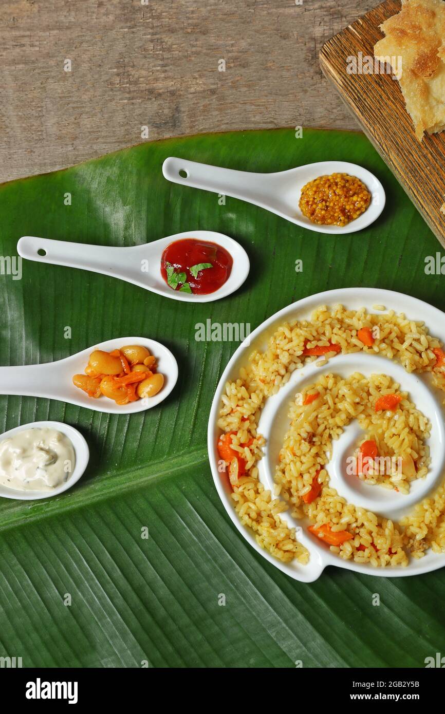 Fried rice with flat bread and spices on banana leaf over wooden ...