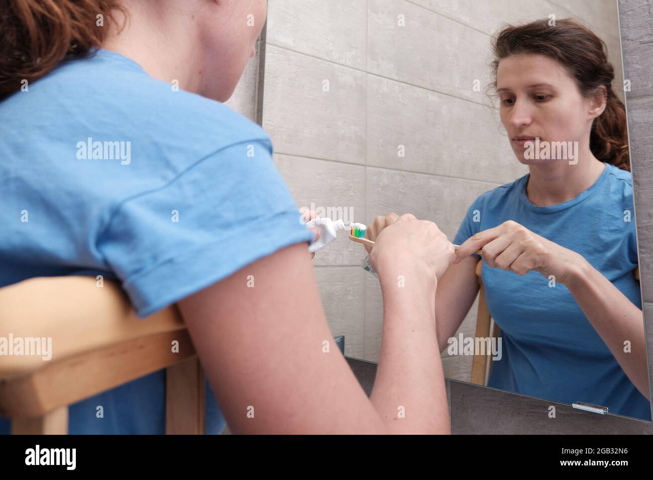 A woman on crutches with a broken leg brushes her teeth in the bathroom