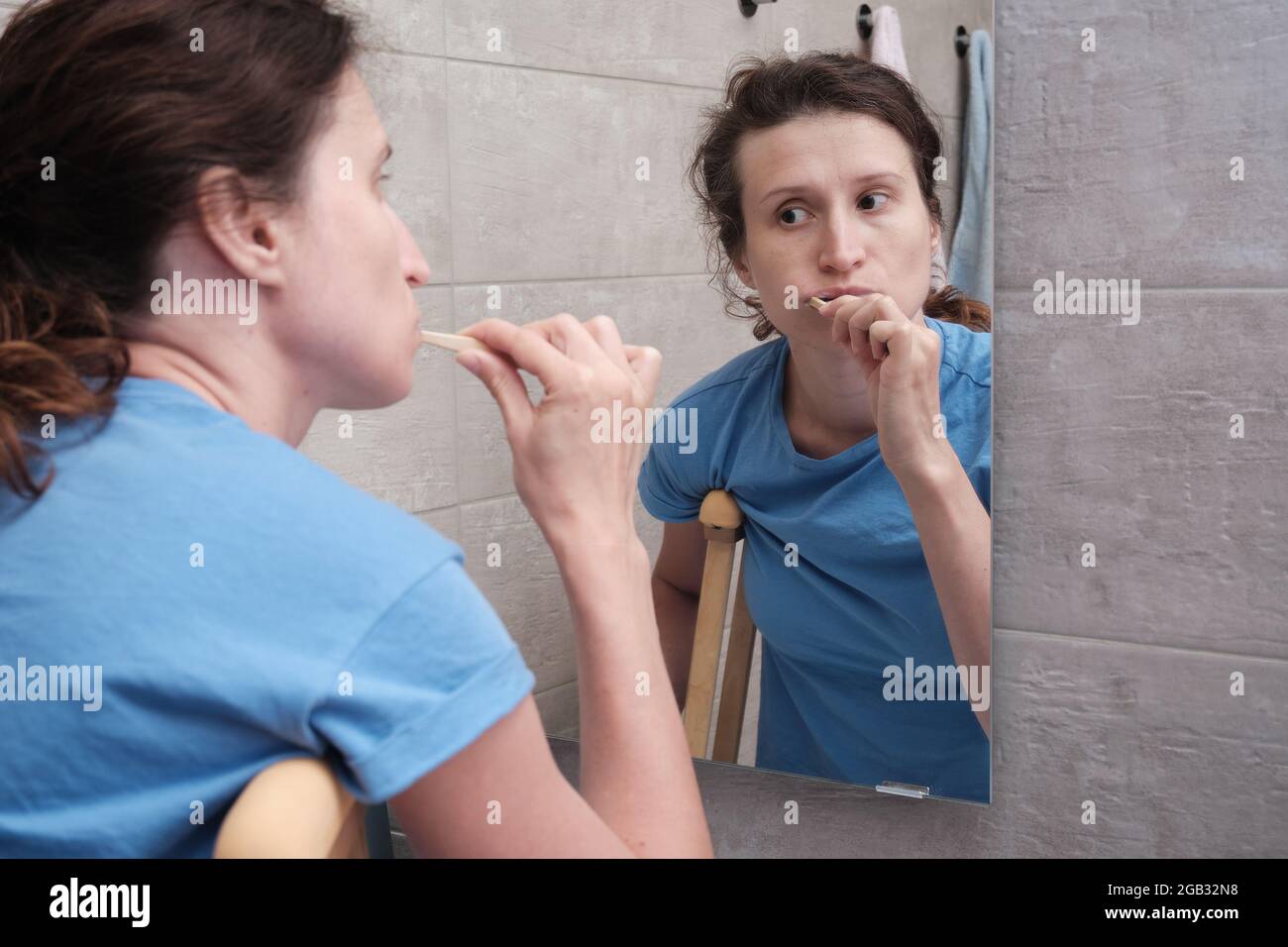 A woman on crutches with a broken leg brushes her teeth in the bathroom