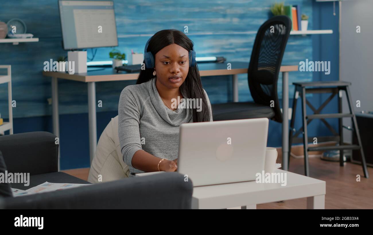 Computer Ole Student blogger with dark skin putting headphones working from home at ...
