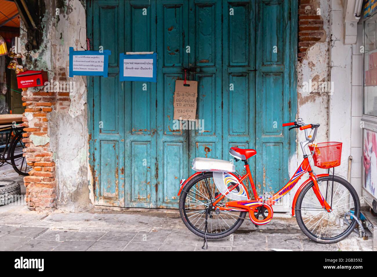 Red bicycle parked by blue doors in CHinatown, Bangkok, Thailand Stock Photo