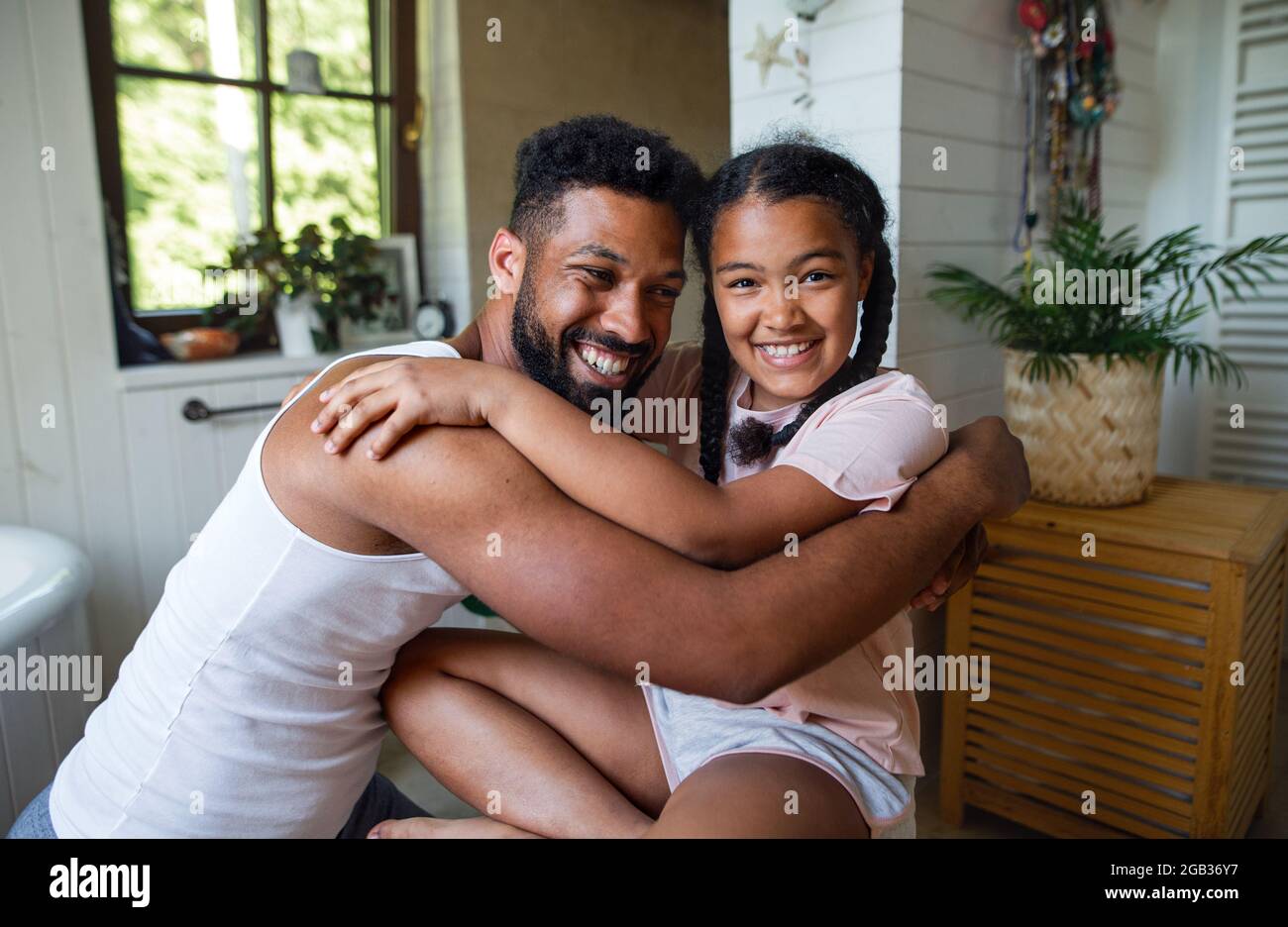 Happy young man with small sister indoors at home, hugging. Stock Photo