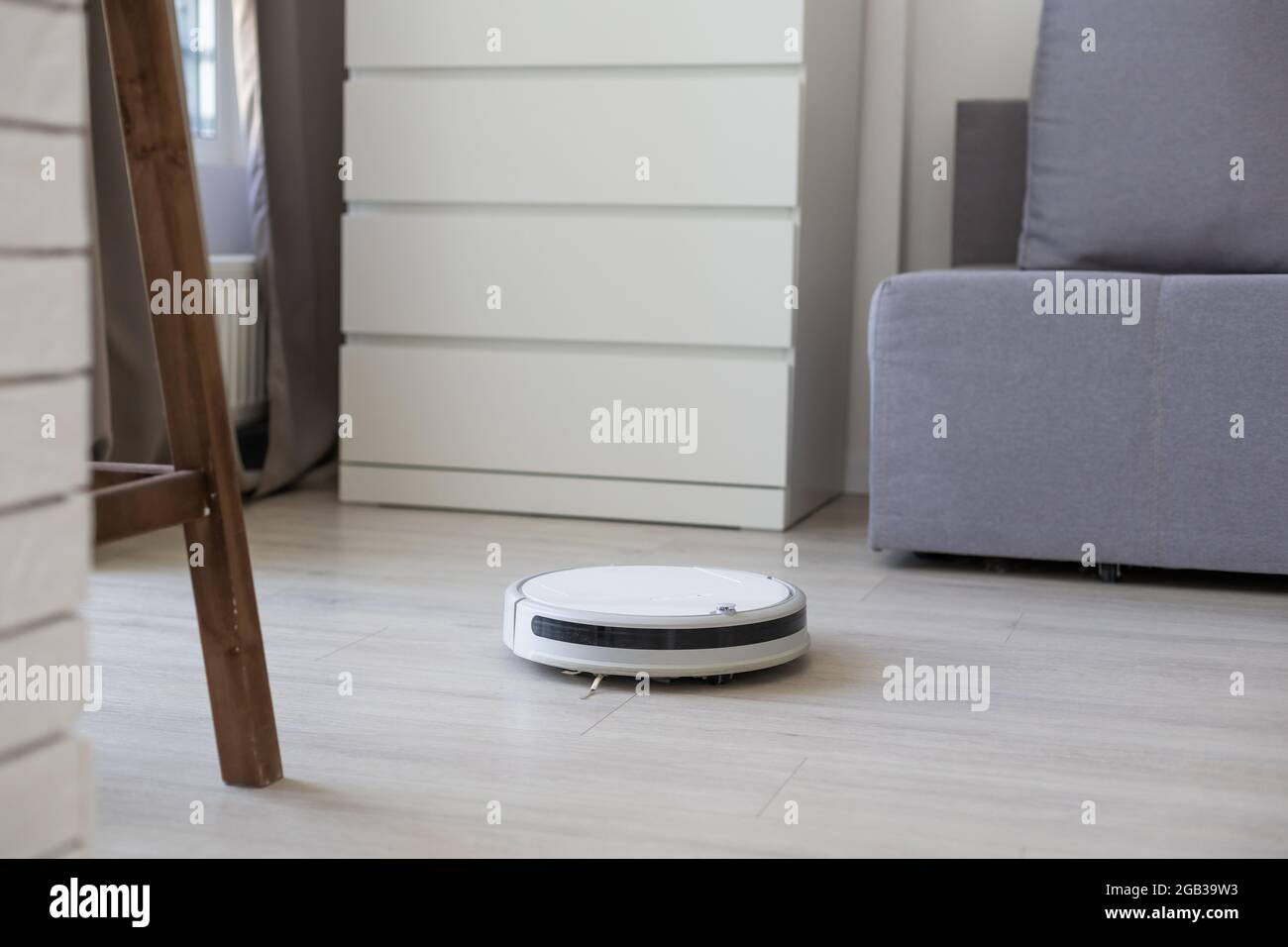 Smart House. Vacuum cleaner robot runs on wood floor in a living room ...
