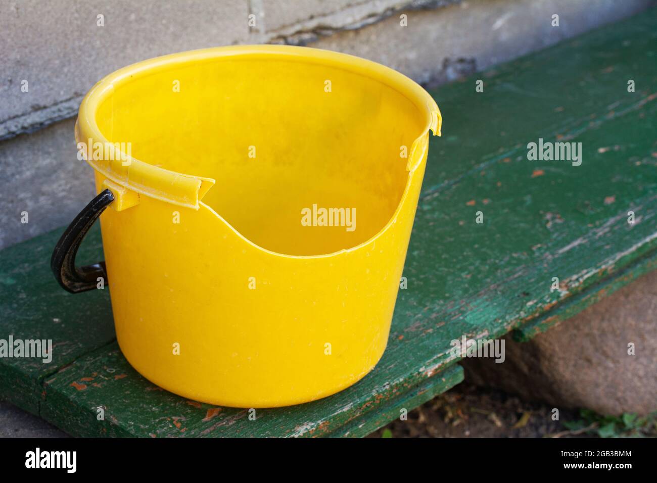 Empty dirty broken yellow plastic bucket on green bench Stock Photo Alamy