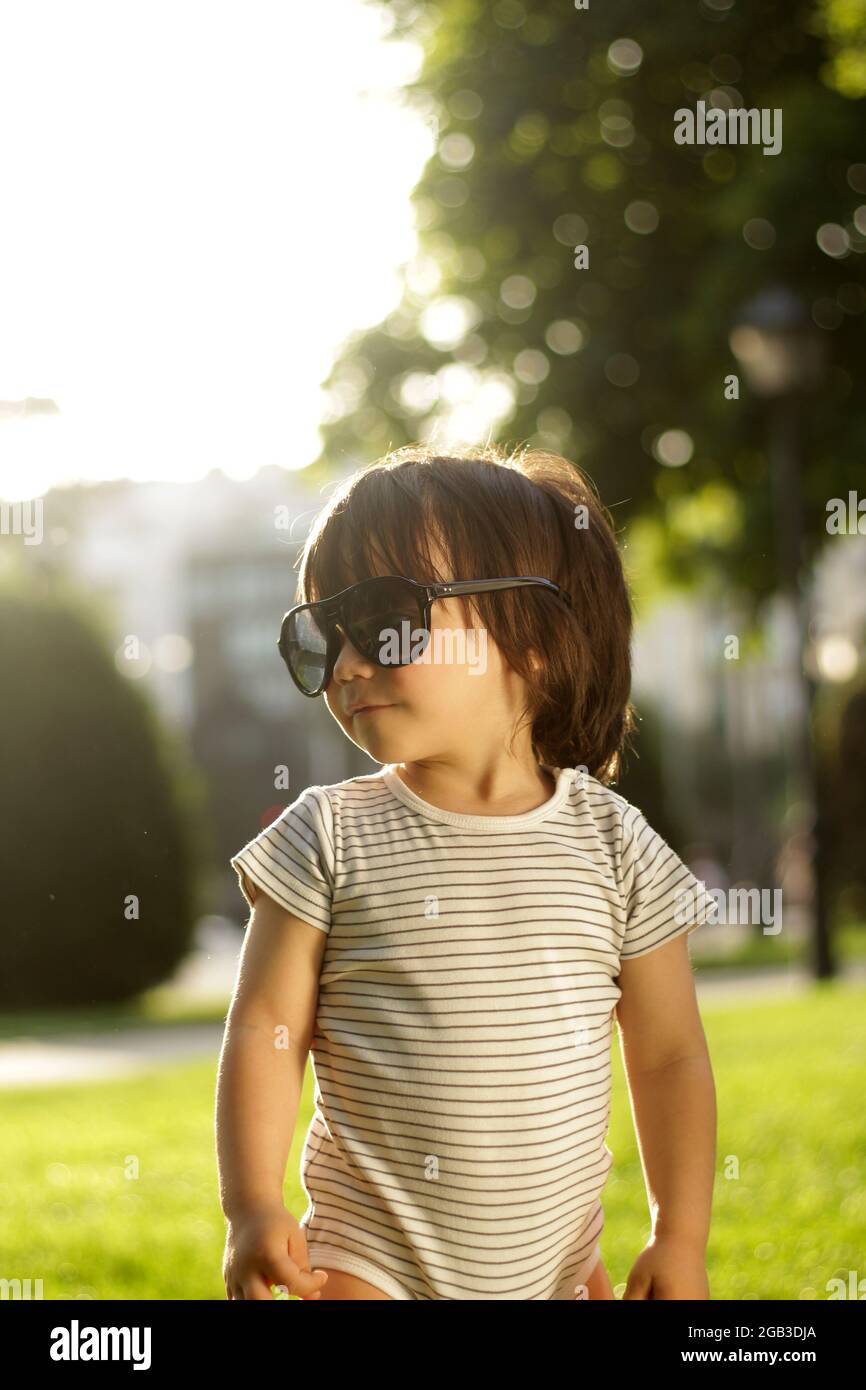 little 1-year-old latin boy in the park at sunset with his father's sunglasses on Stock Photo