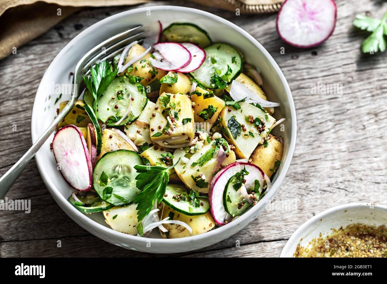 Potato with Cucumber Radish Salad in a wooden bowl Stock Photo