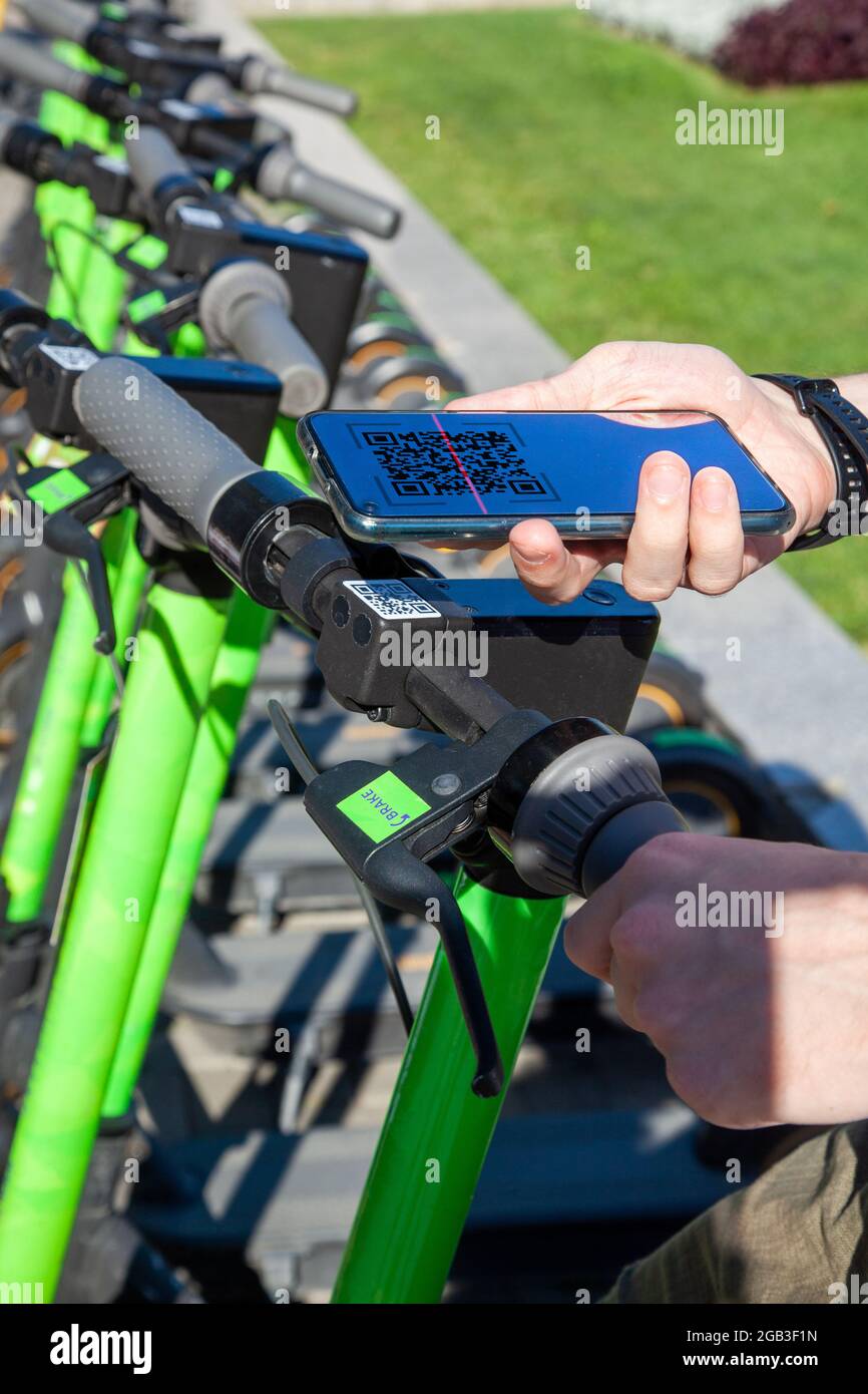 A young man rents an electric scooter by scanning the QR code with a