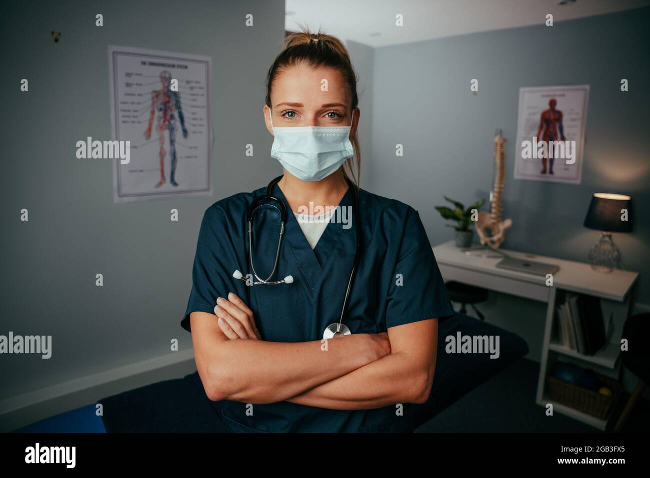 Caucasian female nurse standing in doctors office wearing surgical mask Stock Photo