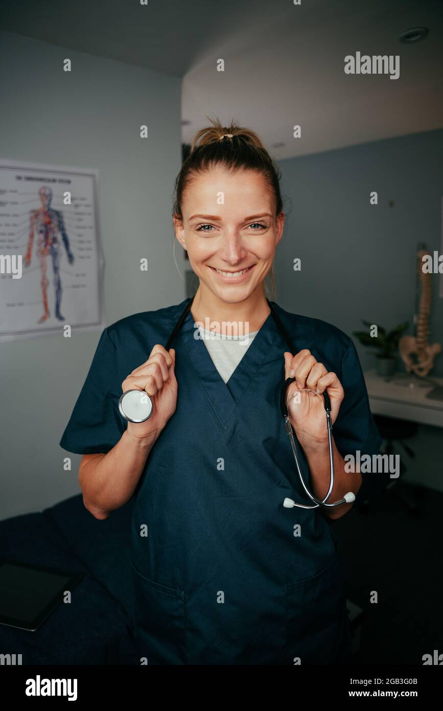 caucasian female nurse standing in doctors office wearing stethoscope Stock Photo