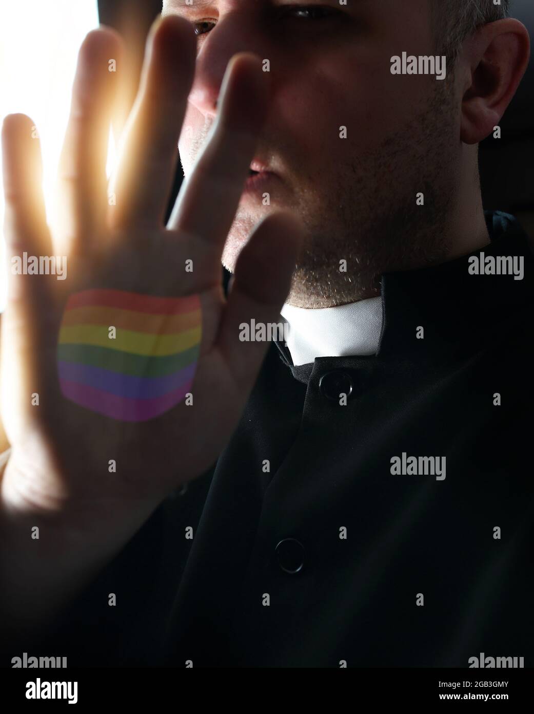 priest with colorful lgbt flag on hand in cassock Stock Photo