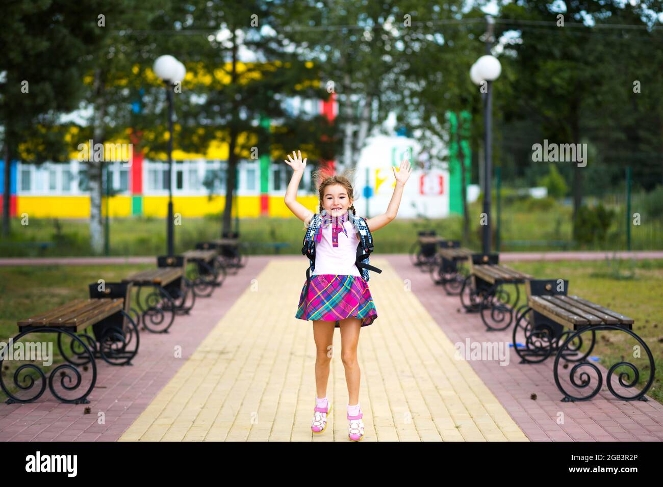 Cheerful girl with a backpack and in a school uniform in the school ...