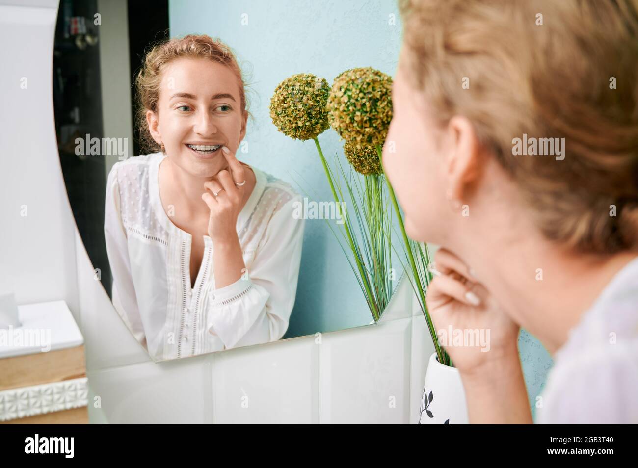 Woman with orthodontic brackets on teeth looking in the mirror