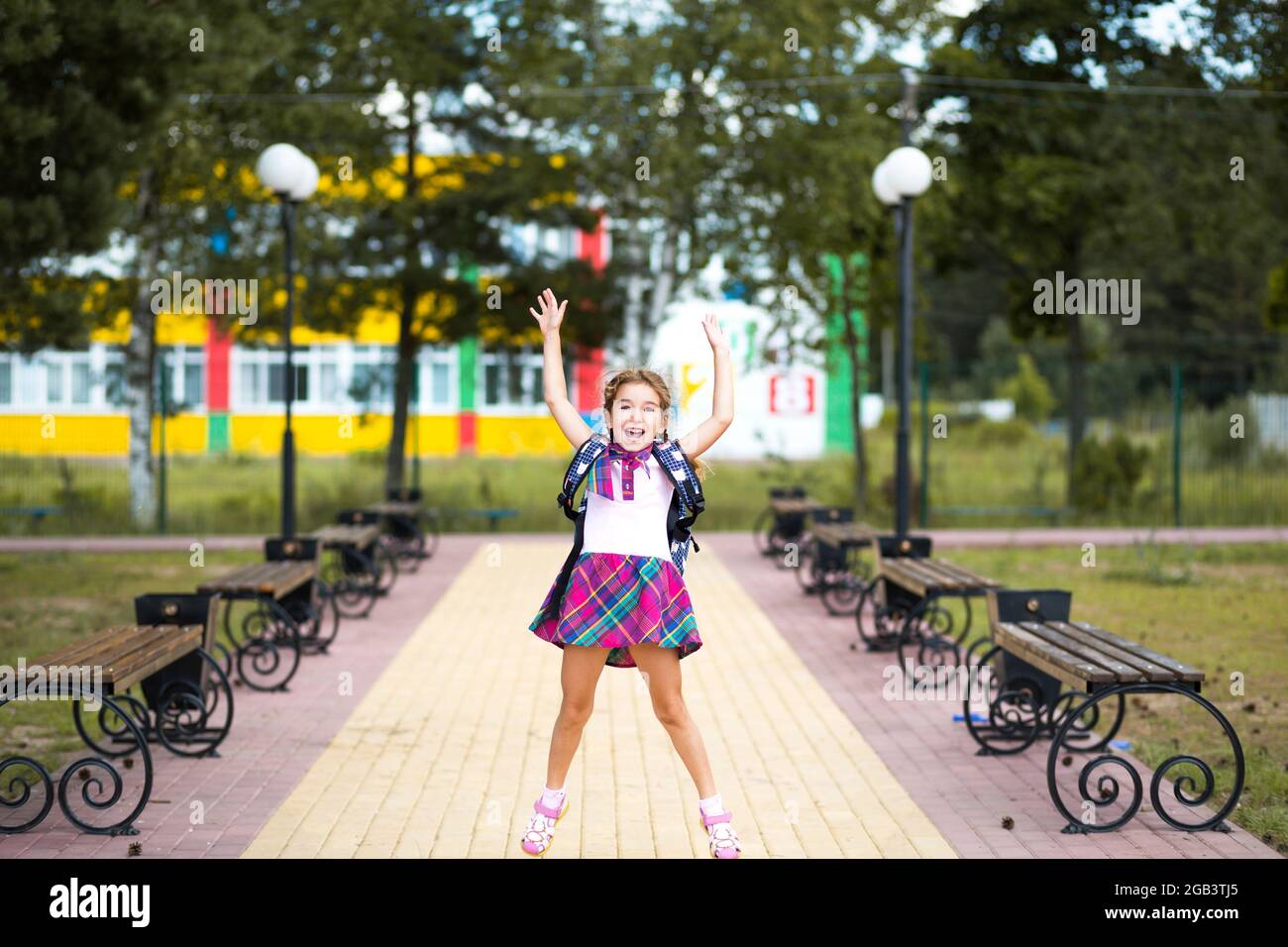Cheerful girl with a backpack and in a school uniform in the school ...