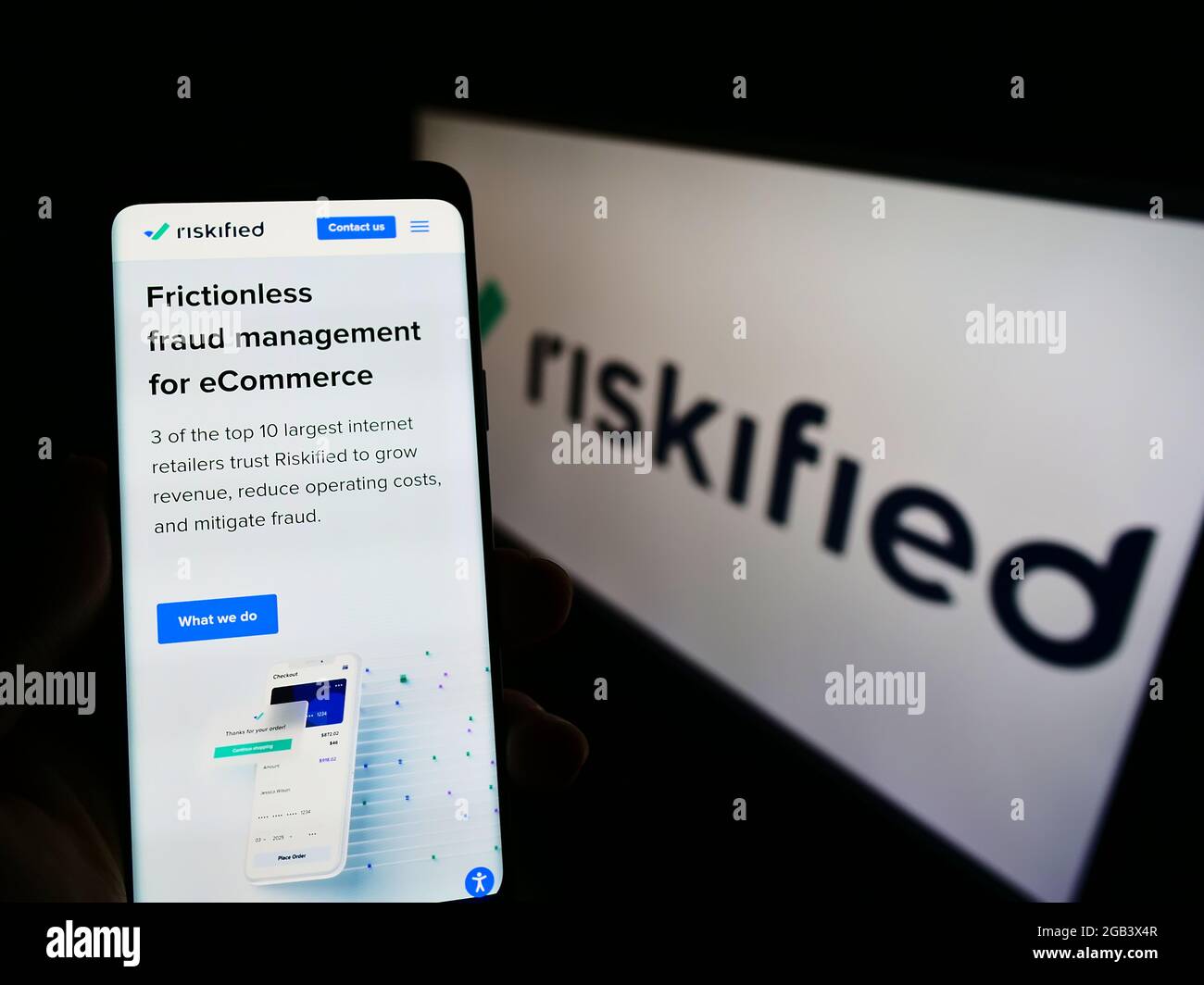 Person holding smartphone with website of fraud prevention software company Riskified Ltd. on screen with logo. Focus on center of phone display. Stock Photo