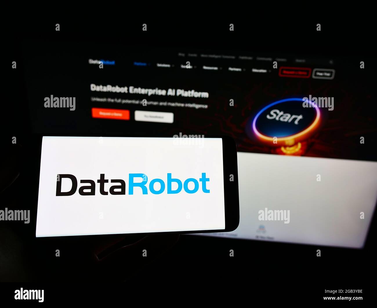 Person holding cellphone with logo of American augmented intelligence company DataRobot Inc. on screen in front of webpage. Focus on phone display. Stock Photo