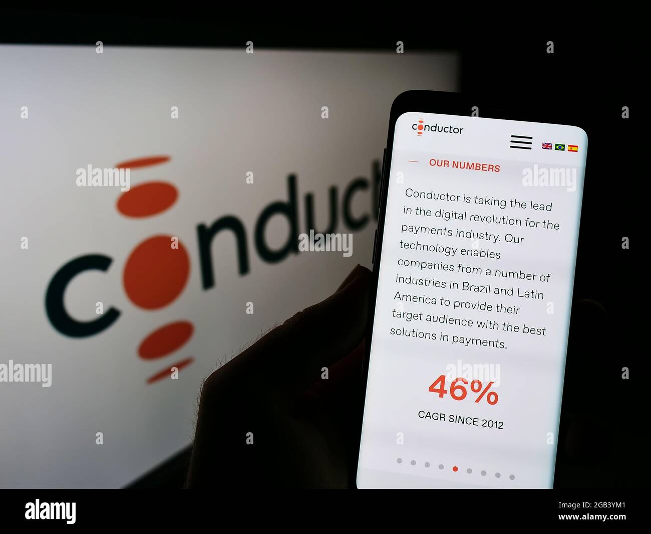 Person holding cellphone with webpage of Brazilian payment company Conductor Technology Ltd. on screen with logo. Focus on center of phone display. Stock Photo