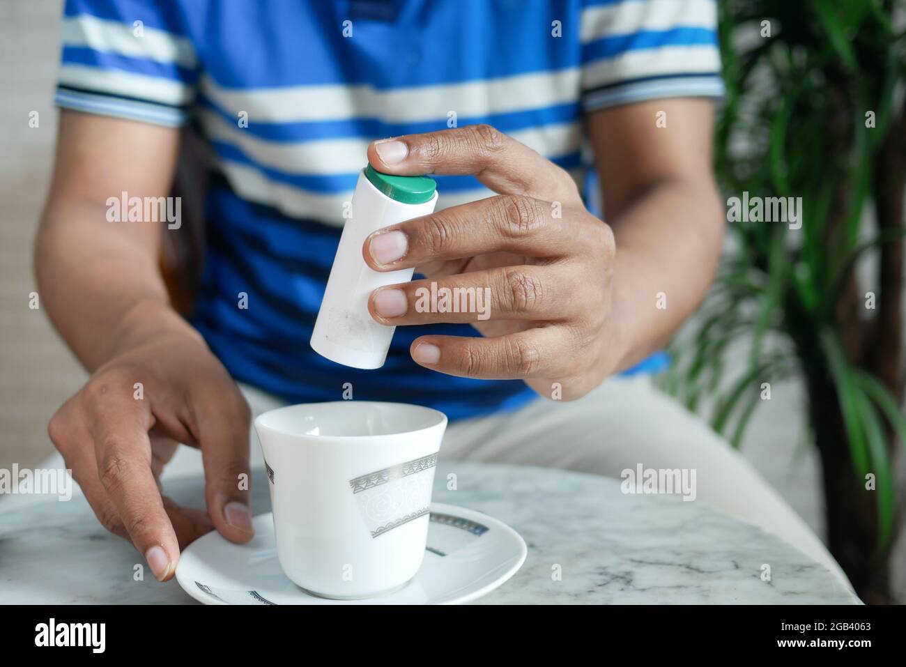 young man putting artificial sweetener in tea, Stock Photo