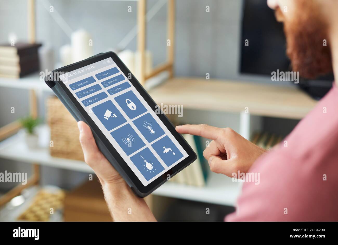 Man using an app on a modern tablet computer to control the system of his Smart House Stock Photo