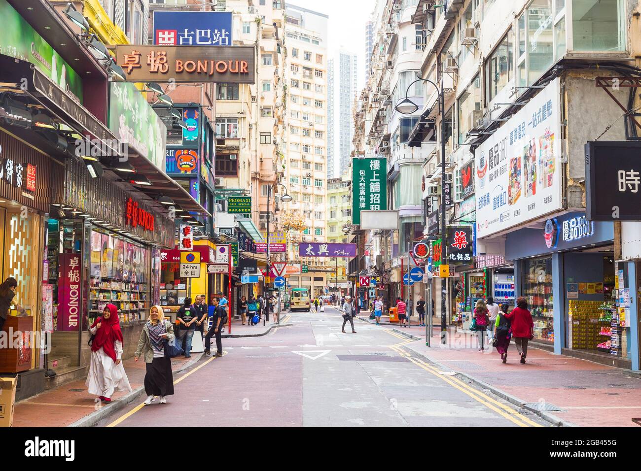 HONG KONG - 9TH APRIL 2017: Streets of Hong Kong during the day showing typical facades and architecture. A person can be seen crossing the road. Stock Photo
