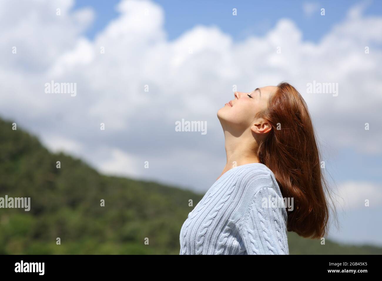 Profile of a woman breathing fresh air in the mountain with a cloudy ...