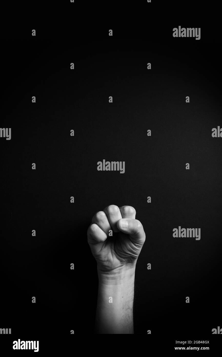 Dramatic B&W image of male hand demonstrating ASL American sign language letter S with empty copy space for editors Stock Photo
