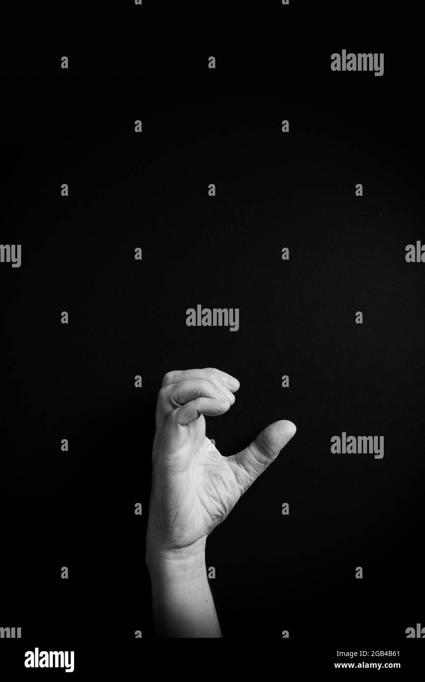 Dramatic B&W image of male hand demonstrating ASL American sign language letter C with empty copy space for editors Stock Photo