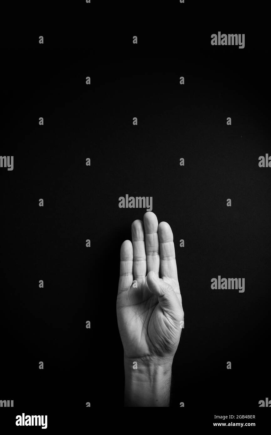 Dramatic B&W image of male hand demonstrating ASL American sign language letter B with empty copy space for editors Stock Photo