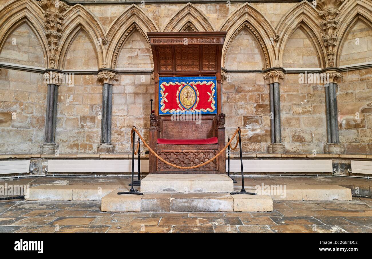 A roped off ceremonial wooden chair (with colourful tapestry of Mary