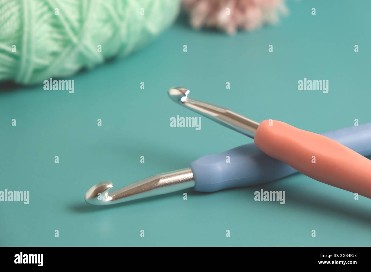 two knitting multicolored crochet hooks on a blue background Stock Photo
