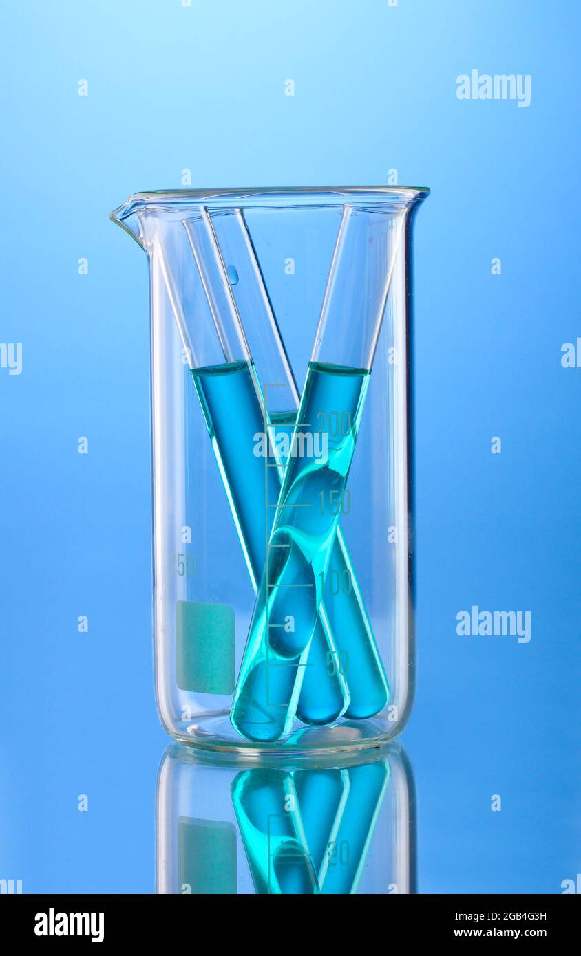 Laboratory tubes with blue liquid in measuring beaker with reflection on blue background Stock
