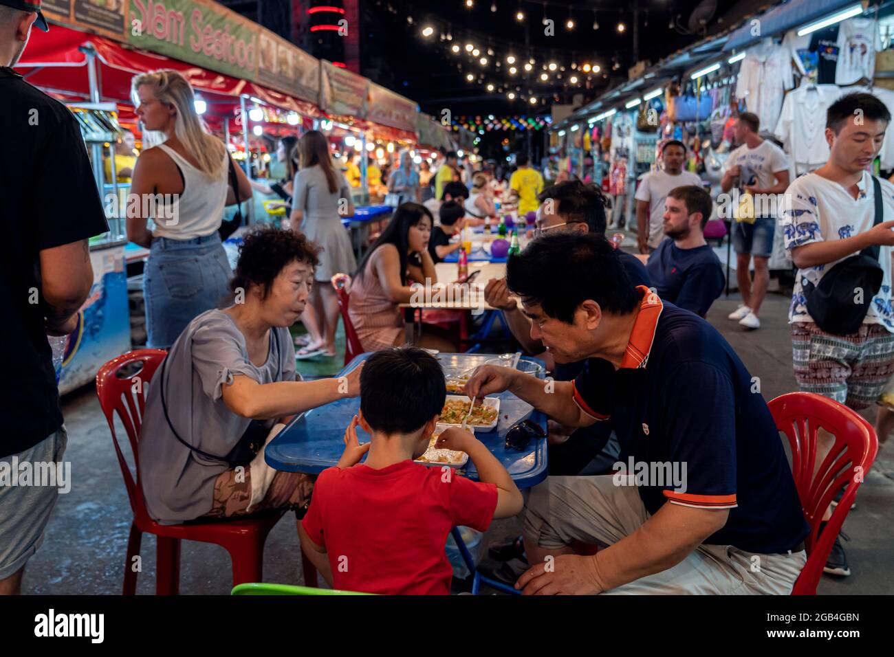 Asian family tourists eat local thai food on the street at phuket market Thailand, Phuket, December 30, 2019 Stock Photo