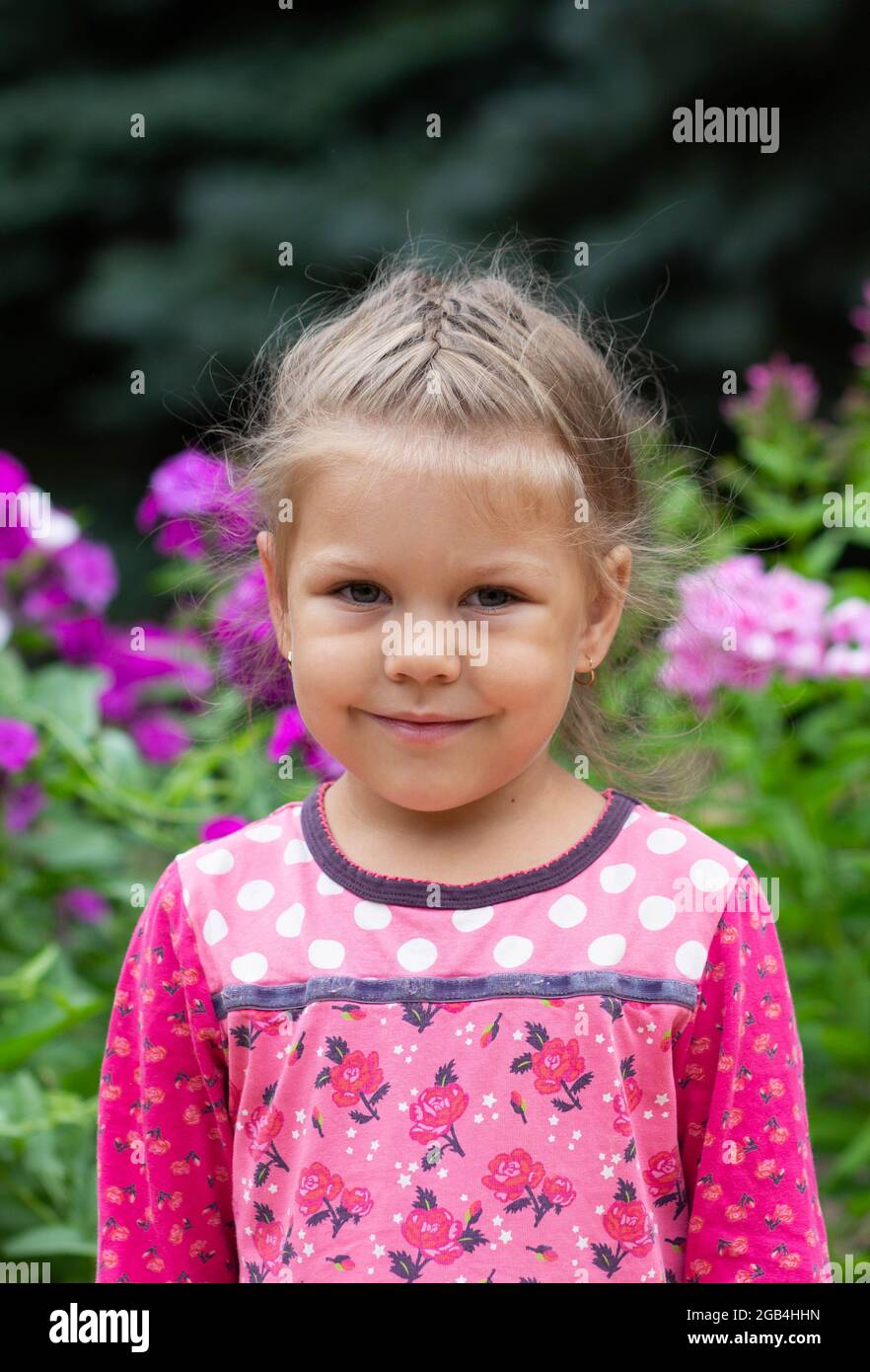 Portrait of shy caucasian girl of four years old looking at camera in summer park Stock Photo
