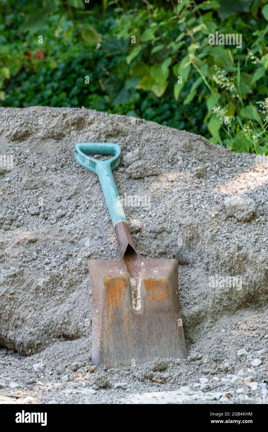 builders shovel, shovel on pile of ballast, builders shovel left on pile of sand, discarded