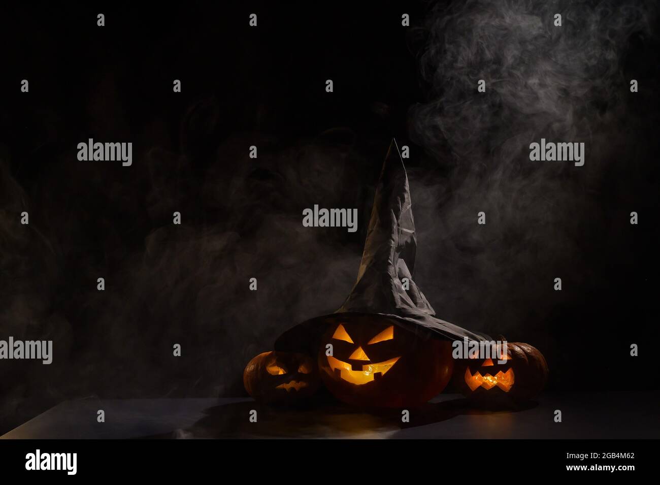Three jack o lanterns glow in the dark amidst the fog. Halloween ...