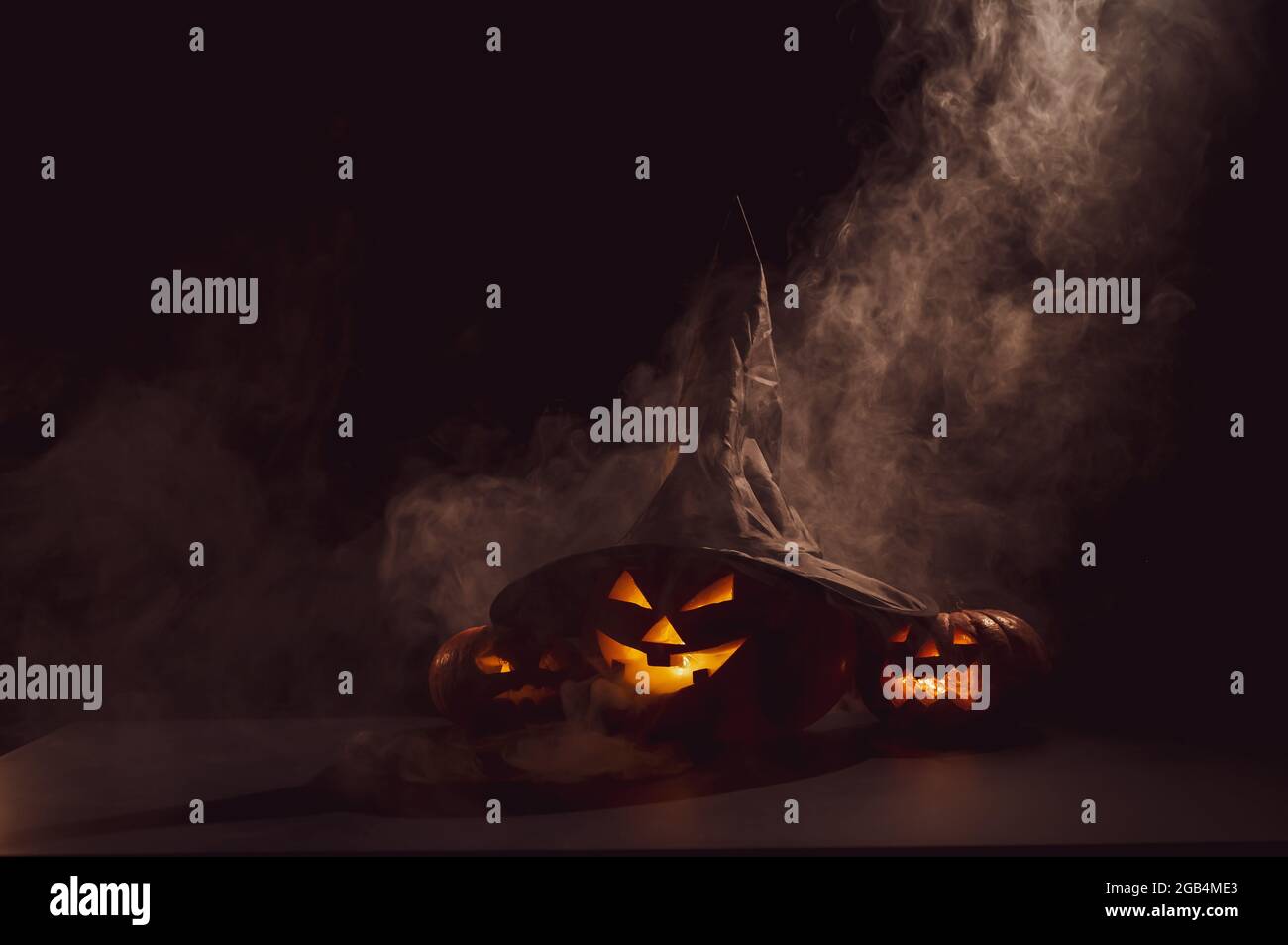 Three jack o lanterns glow in the dark amidst the fog. Halloween ...