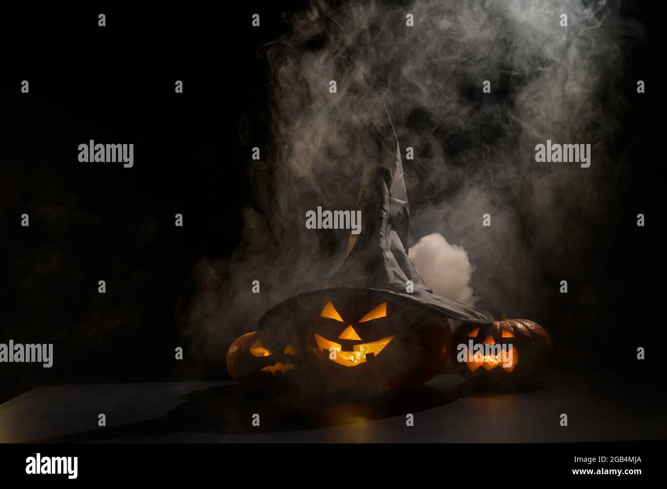 Three jack o lanterns glow in the dark amidst the fog. Halloween ...