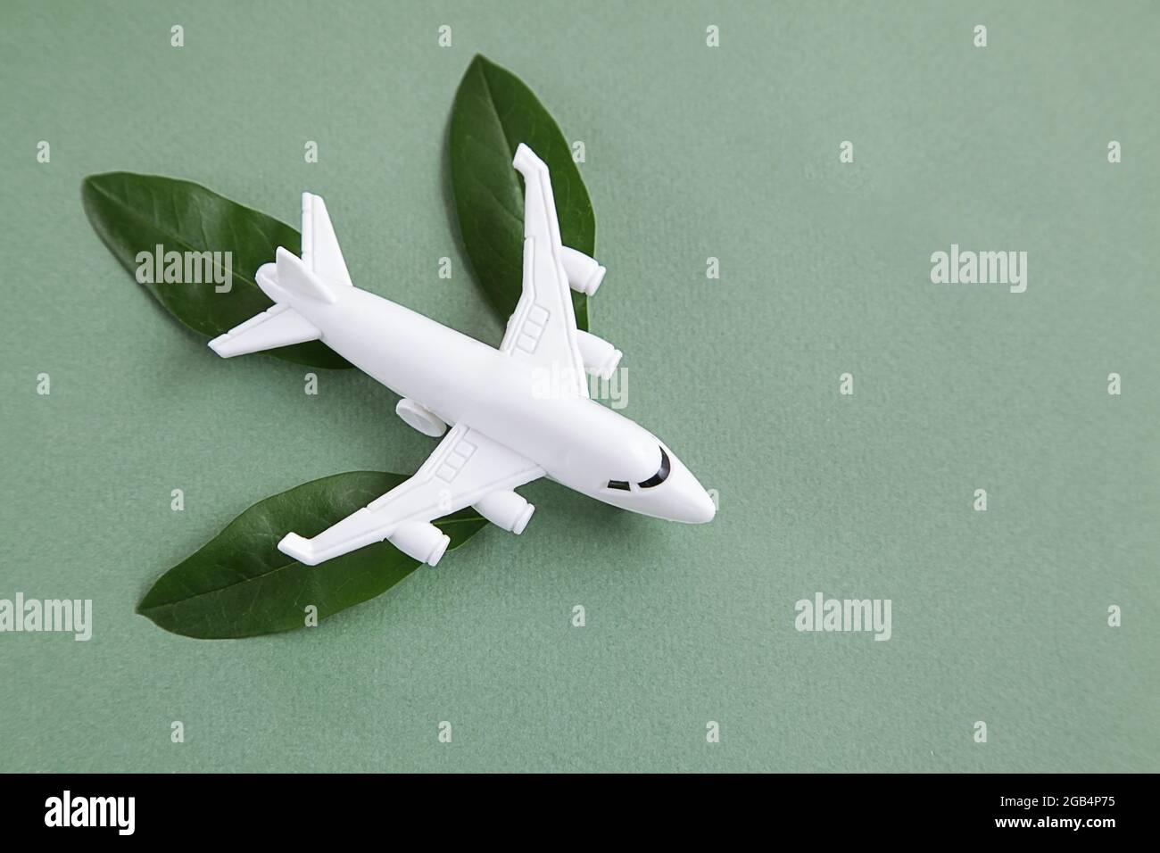White airplane on green background. Sustainable Aviation Fuel, clean green energy concept. Stock Photo