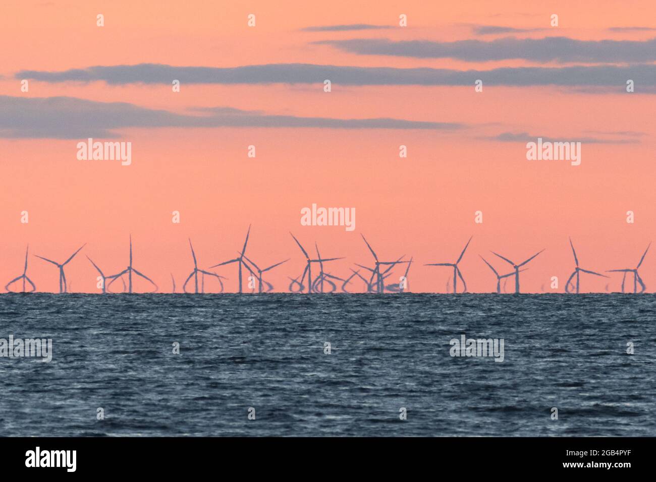 Wind farm in the Irish Sea at dusk. A mirage effect causes the turbines ...