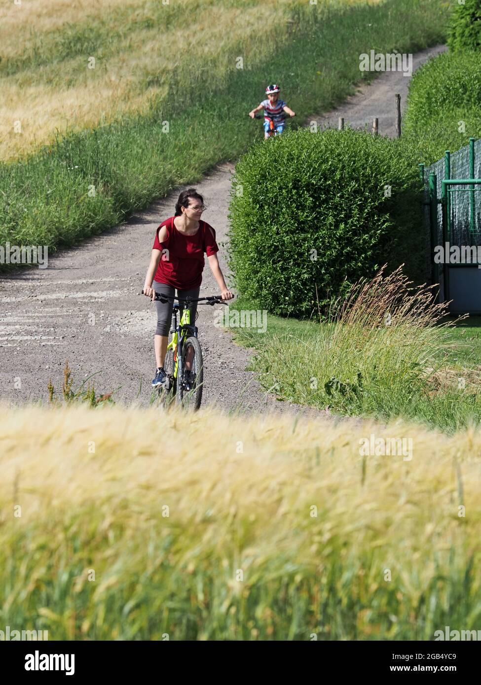 Mother with her son ride a bike in the summer countryside Stock Photo