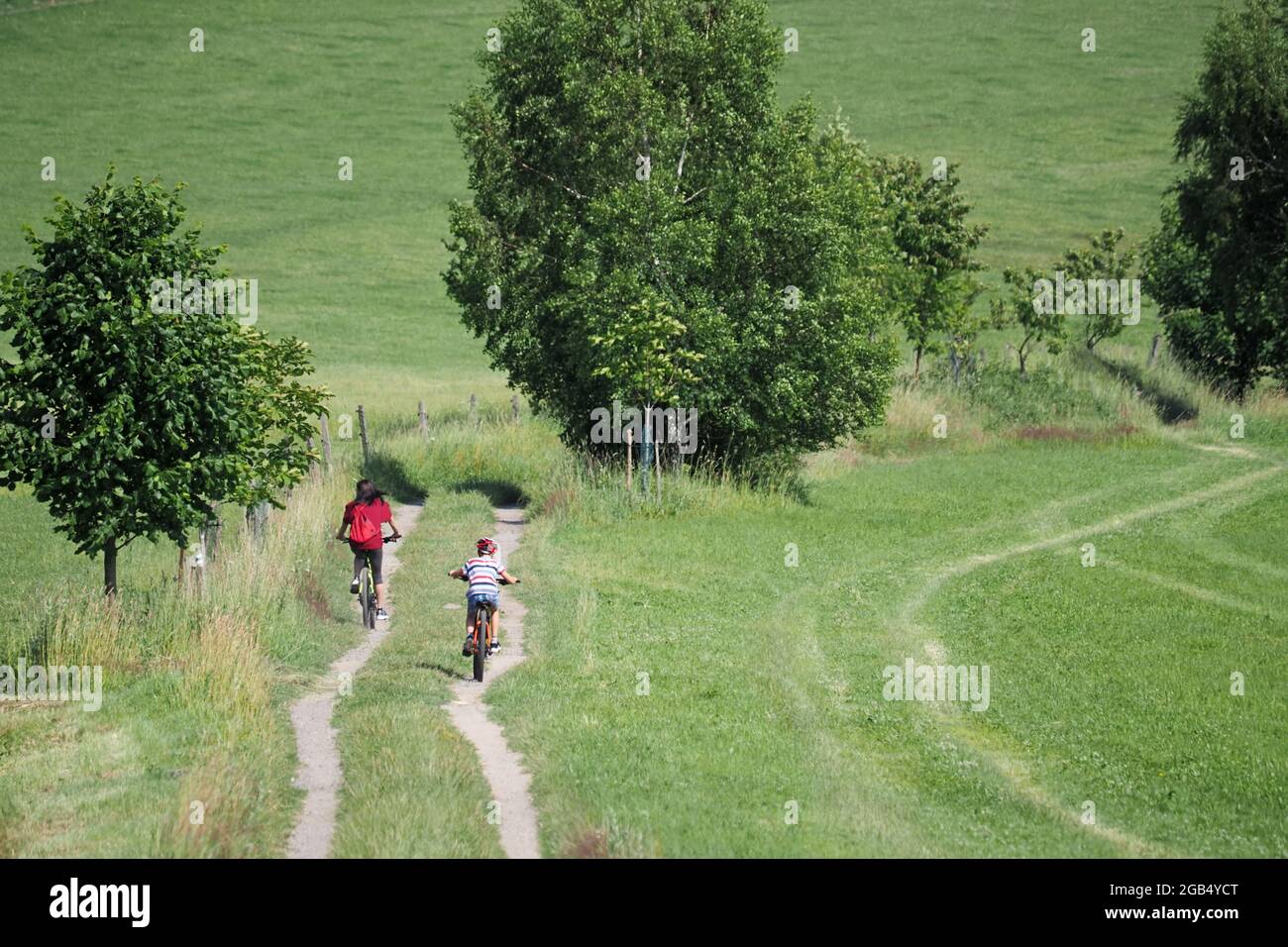 Mother with her son ride a bike in the summer countryside Stock Photo