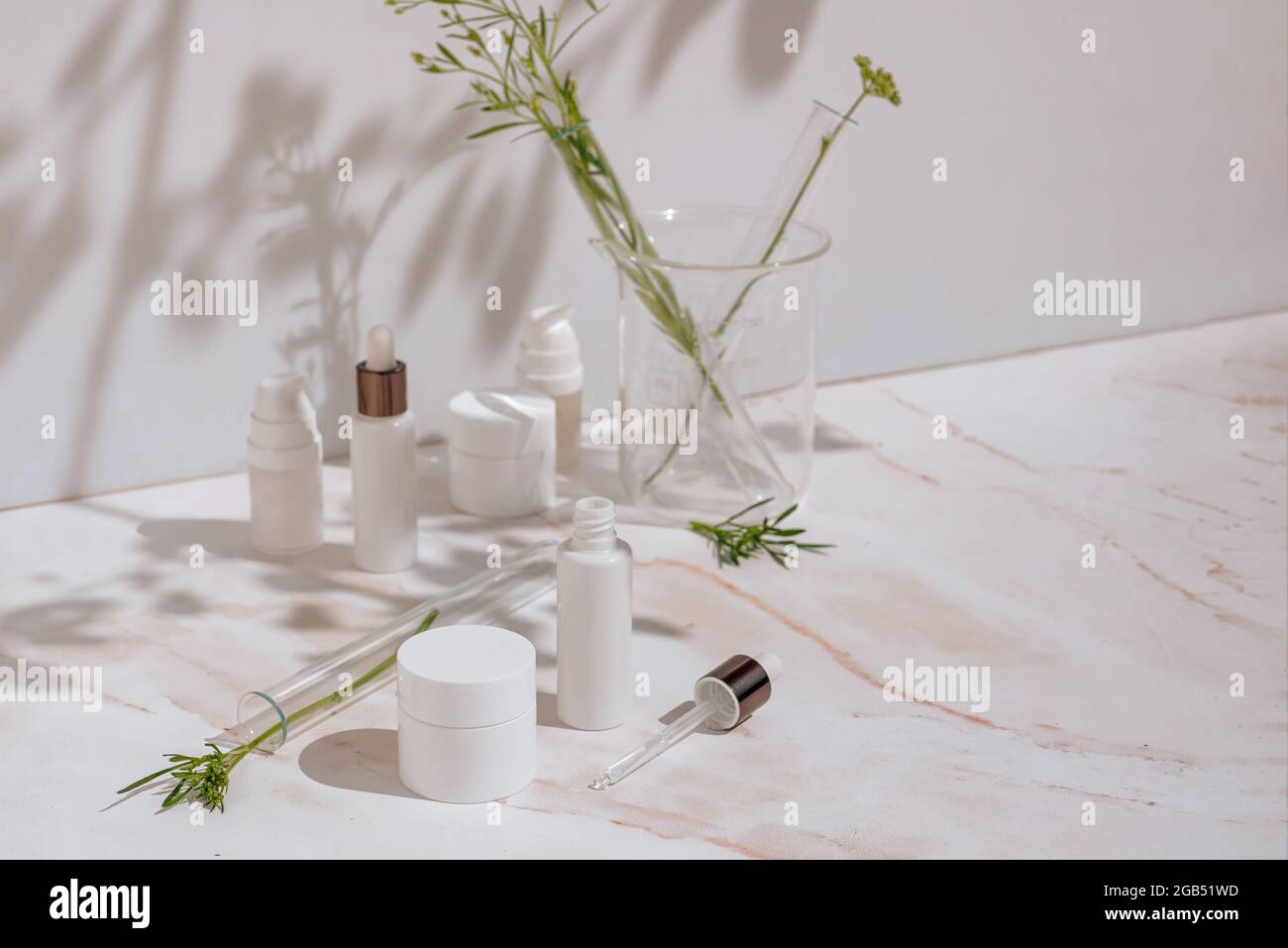 Natural cosmetic products in white packaging with laboratory glassware. Science and skincare concept Compositions with cosmetic packaging in a medical Stock Photo